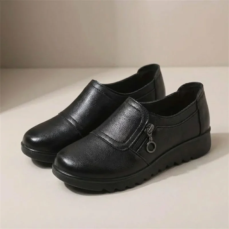 Paire de mocassins femme compensés noire en simili cuir avec zip latéral, vue de trois quarts.