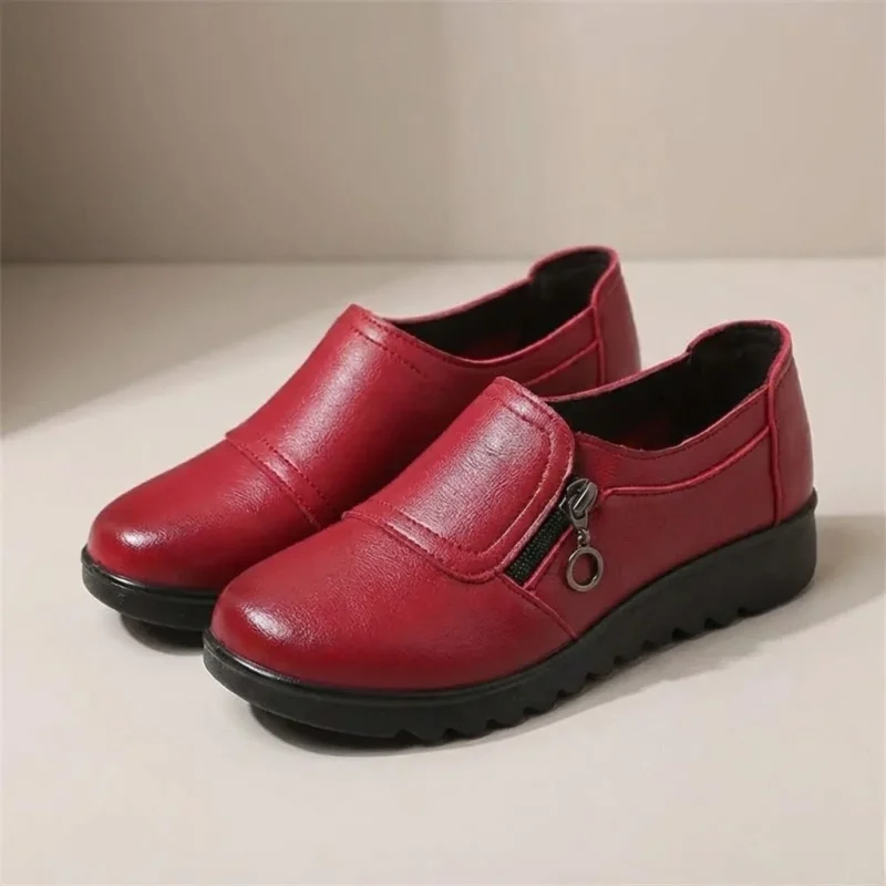 Paire de mocassins femme compensés rouges en simili cuir avec zip latéral, vue de trois quarts.