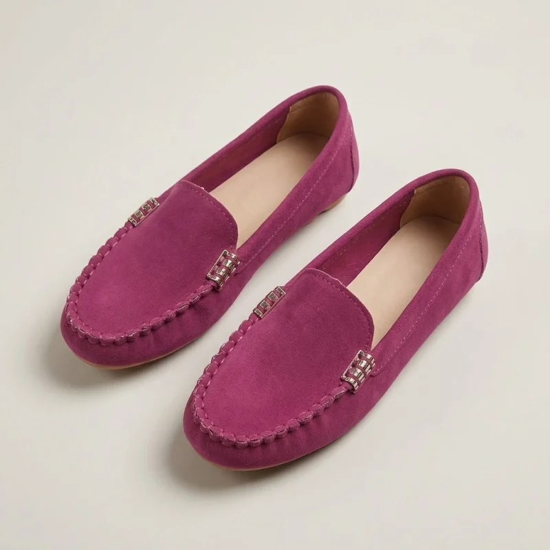 Mocassin-rose-plat-en-daim Mocassins en daim fuchsia pour femme, design épuré avec détails métalliques, présentés sur un fond de studio blanc avec éclairage doux.